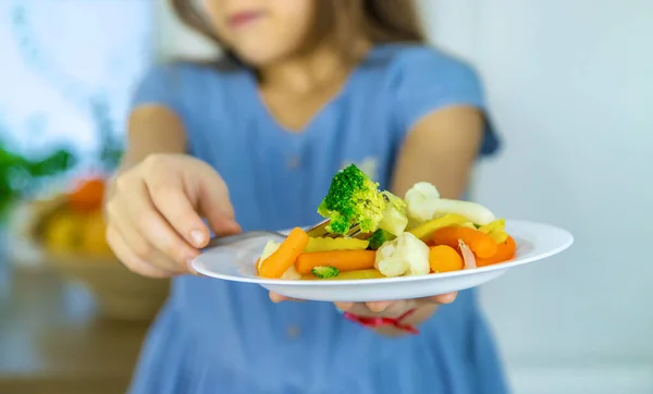 Das Kind isst Gemüse auf einem Stuhl. Selektiver Fokus. — Stockfoto