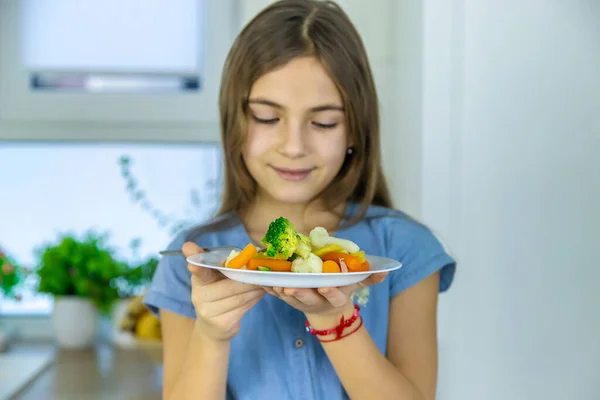 El niño come verduras en una silla. Enfoque selectivo. — Foto de Stock