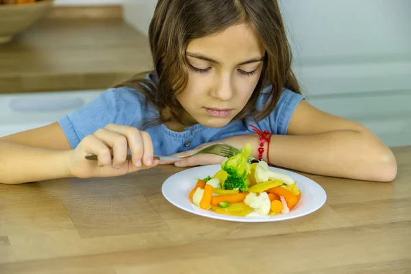 El niño come verduras en una silla. Enfoque selectivo. — Foto de Stock