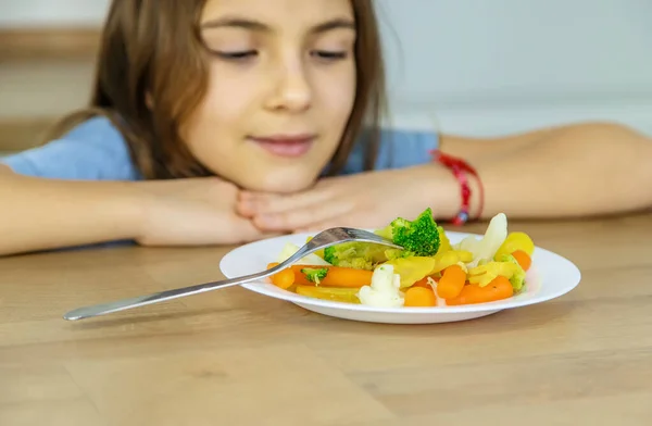 Het kind eet groenten op een stoel. Selectieve focus. — Stockfoto