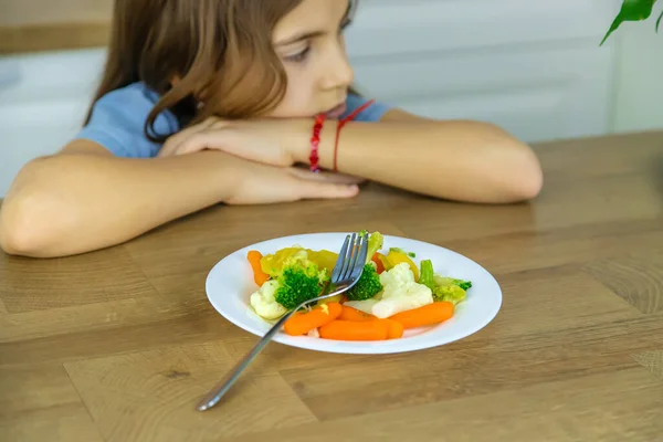 A criança come verduras em uma cadeira. Foco seletivo. — Fotografia de Stock