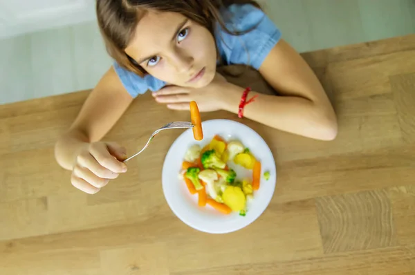 어린이는 의자에서 야채를 먹는다. 선택적 초점. — 스톡 사진