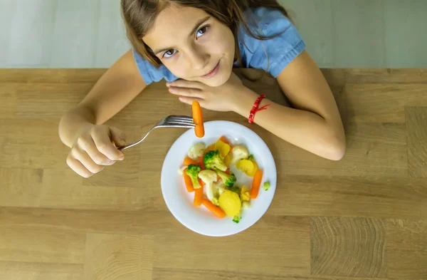 El niño come verduras en una silla. Enfoque selectivo. — Foto de Stock