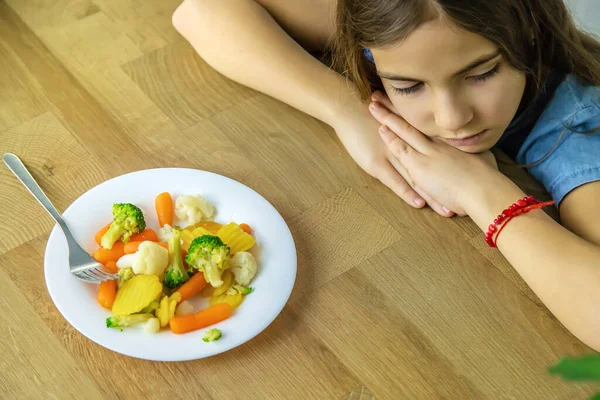 Το παιδί τρώει λαχανικά σε μια καρέκλα. Επιλεκτική εστίαση. — Φωτογραφία Αρχείου