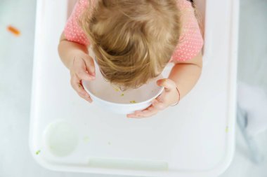 Bebek sandalyede sebze yiyor. Seçici odak.