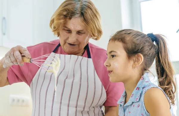 Mutfaktaki çocuk ve büyükanne hamuru pişirir. Seçici odaklanma. Yiyecek..