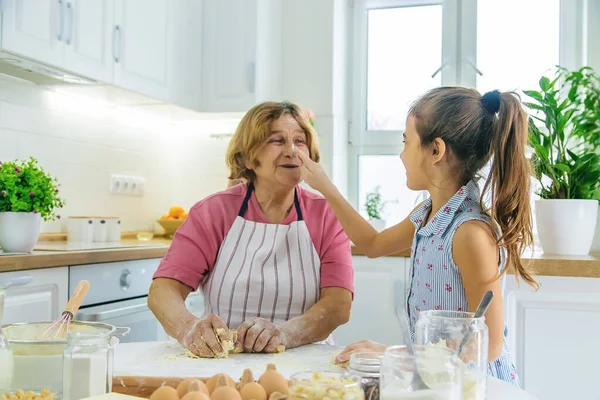 Mutfaktaki çocuk ve büyükanne hamuru pişirir. Seçici odaklanma. Yiyecek..