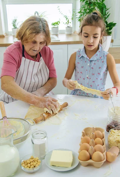 Mutfaktaki çocuk ve büyükanne hamuru pişirir. Seçici odaklanma. Yiyecek..