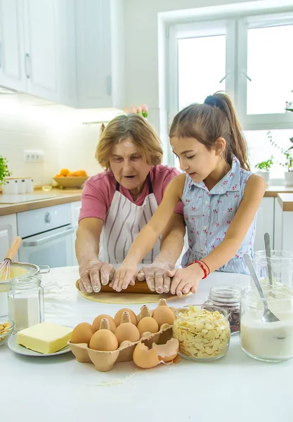 Mutfaktaki çocuk ve büyükanne hamuru pişirir. Seçici odaklanma. Yiyecek..
