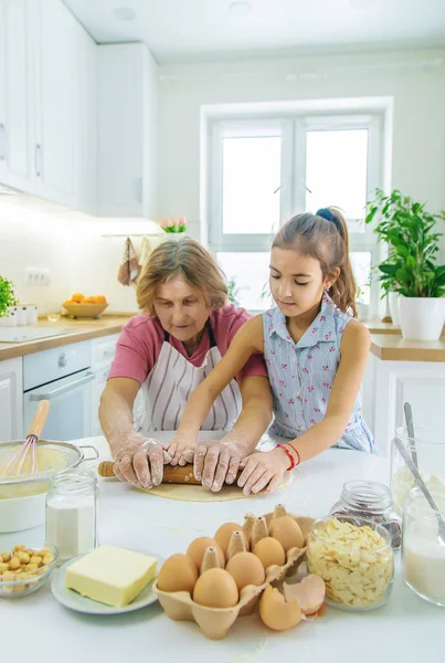 Mutfaktaki çocuk ve büyükanne hamuru pişirir. Seçici odaklanma. Yiyecek..