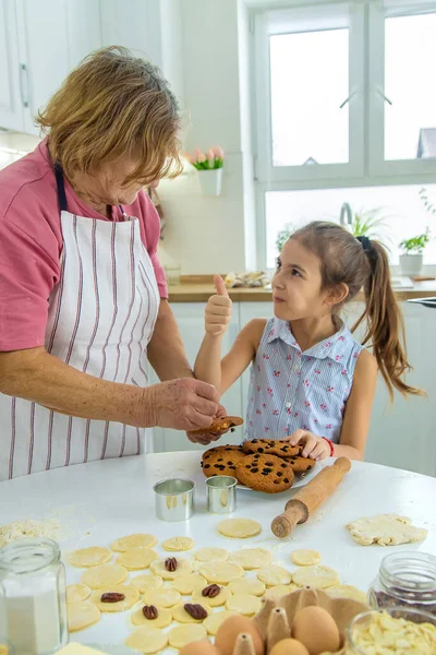 Babička a vnučka pečou sušenky v kuchyni. Selektivní zaměření. — Stock fotografie