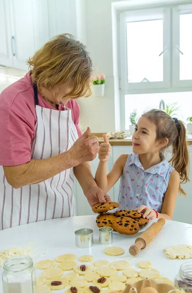 Babička a vnučka pečou sušenky v kuchyni. Selektivní zaměření. — Stock fotografie