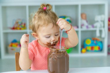 Bebek çok fazla çikolata yiyor. Seçici odaklanma. Çocuk.