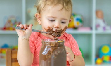 Bebek çok fazla çikolata yiyor. Seçici odaklanma. Çocuk.