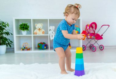 Bir bebek çocuk oyun odasında oyuncaklarla oynar. Seçici odaklanma. Çocuk.