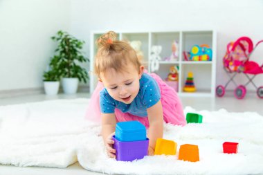Bir bebek çocuk oyun odasında oyuncaklarla oynar. Seçici odaklanma. Çocuk.