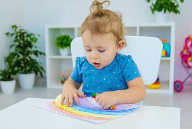 Çocuk bir gökkuşağı çiziyor. Seçici odaklanma. Bebeğim..