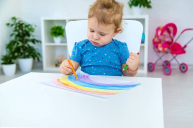 Çocuk bir gökkuşağı çiziyor. Seçici odaklanma. Bebeğim..