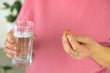 Omega 3, yaşlı kadın içiyor. Seçici odaklanma. İnsanlar.