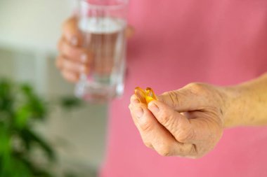 Omega 3, yaşlı kadın içiyor. Seçici odaklanma. İnsanlar.