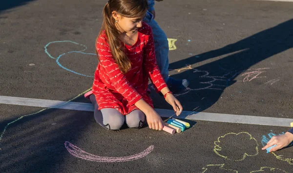 Children draw with chalk on the pavement. Selective focus. — Stockfoto