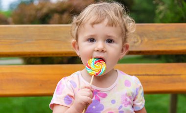 Bebek parkta bir lolipop yiyor. Seçici odaklanma. Çocuk.