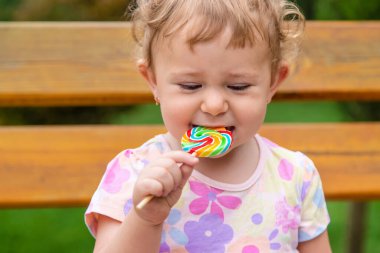 Bebek parkta bir lolipop yiyor. Seçici odaklanma. Çocuk.