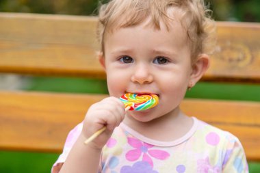 Bebek parkta bir lolipop yiyor. Seçici odaklanma. Çocuk.
