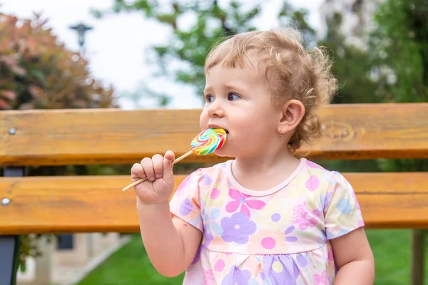 아기는 공원에서 롤리팝을 먹는다 선택적 집중입니다 — 스톡 사진