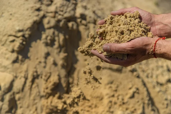 Sand in the hands of a man. Selective focus. Nature.