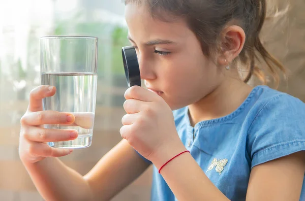 孩子用玻璃杯中的放大镜检查水 有选择的重点 — 图库照片