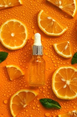 Bottle of cosmetics and drops of liquid, moisturizing orange. Hyaluronic acid. Selective focus. Spa.