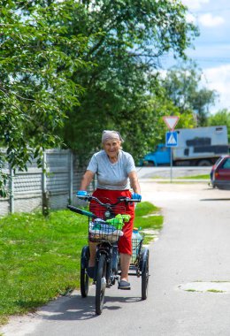 An old woman rides a bicycle. Selection focus. Nature.