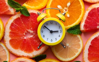 Clock and citruses summer time concept. Selective focus. Food.
