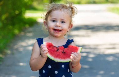 A child eats watermelon in the park. Selective focus. Kid.