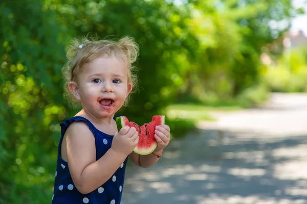 A child eats watermelon in the park. Selective focus. Kid.
