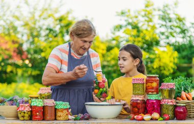 Women with jar preserved vegetables for the winter mother and daughter. Selective focus. Food.