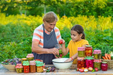 Women with jar preserved vegetables for the winter mother and daughter. Selective focus. Food.
