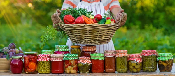 Senior woman preserving vegetables in jars. Selective focus. Food.