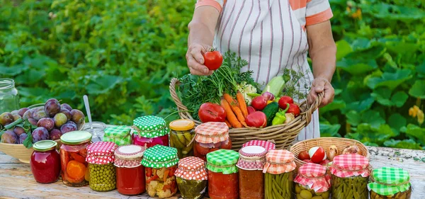 Senior woman preserving vegetables in jars. Selective focus. Food.