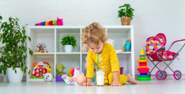 Child drink milk in the room. Selective focus. Kid.