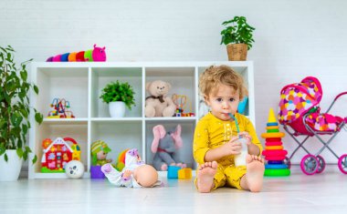 Child drink milk in the room. Selective focus. Kid.