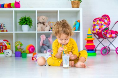 Child drink milk in the room. Selective focus. Kid.