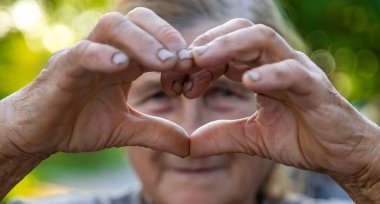 grandmother makes a heart with her hands. Selective focus. People.