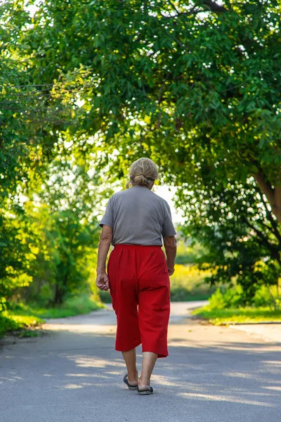 grandma is walking down the road. Selective focus. Nature.
