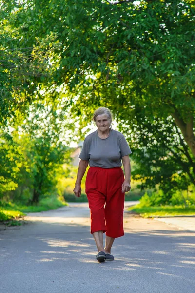 grandma is walking down the road. Selective focus. Nature.