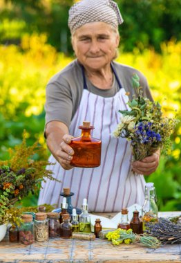 Grandmother makes tinctures from medicinal herbs. Selective focus. People.