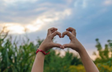 The child makes a heart with his hands. Selective focus. Kid.