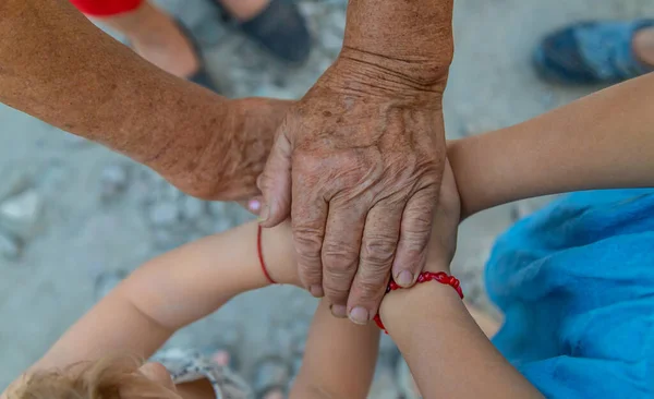 Grandmother and grandchildren friends hands together. Selective focus. People.