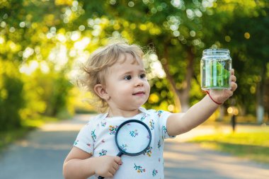 A child is studying a snail in the park. Selective focus. Nature.